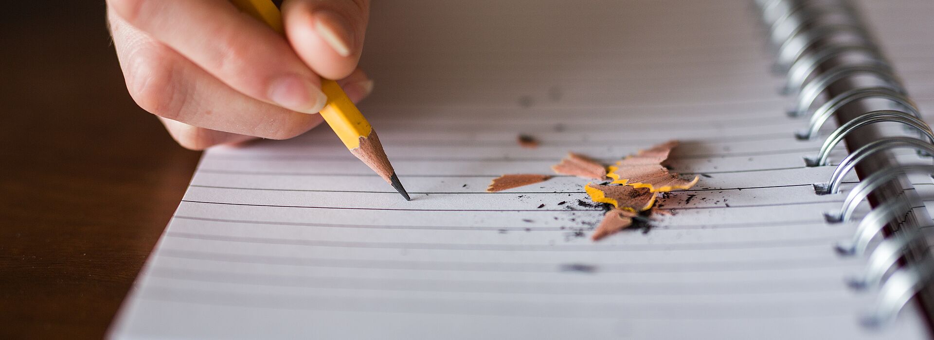 eine Hand mit Bleistift schreibt in einen Notizblock