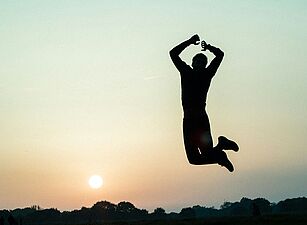 Foto von Marc Najera auf Unsplash Silhouette einer Person, die bei Sonnenuntergang in die Luft springt