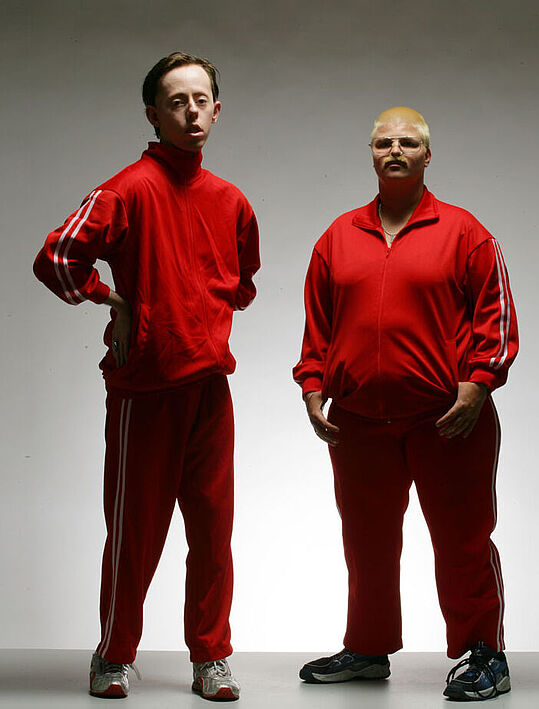 Pressefoto Back to Back, 2 Personen mit roten Trainingsanzug.