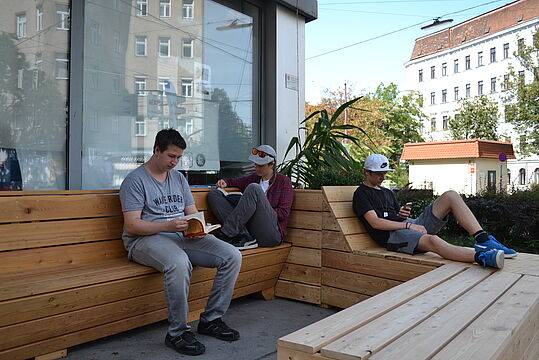 Jugendliche sitzen auf dem Parklet, selbstgebauten Bänken