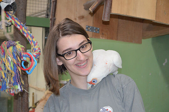 Eine junge Frau mit Papagei auf der Schulter