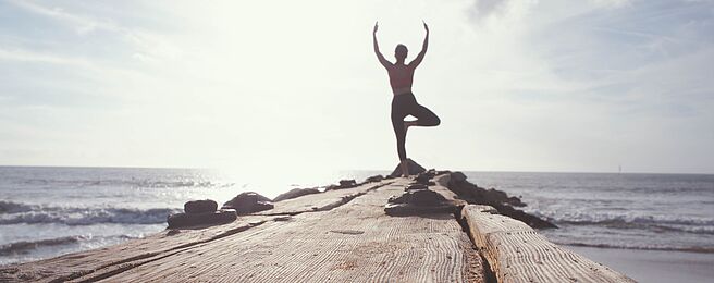 junge Frau macht Yoga auf einem Steg