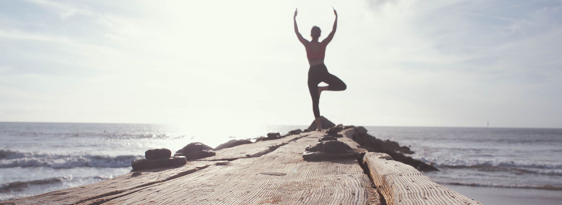 junge Frau macht Yoga auf einem Steg