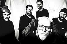 schwarz-weiß Foto von Thomas D, der sich an den Kopf fasst und in die Kamera blickt, dahinter stehen 4 Männer, ebenfalls mit Blick in die Kamera