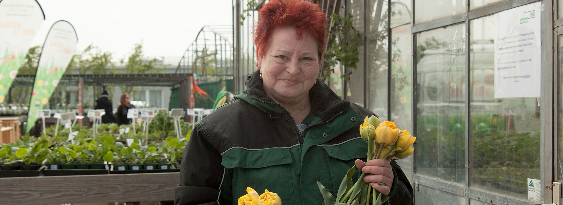 Eine Mitarbeiterin von WUK bio.pflanzen mit Blumen in der Hand