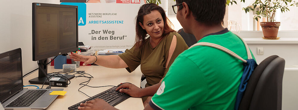 Beraterin erklärt Jugendlichen am Computer den Weg in den Beruf im Rahmen der Arbeitsassistenz