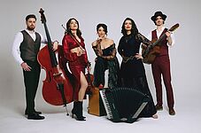 Fünf Personen in eleganter Kleidung posieren vor neutralem Hintergrund, eine spielt Kontrabass, eine hält eine Geige, eine trägt einen Hut und eine Gitarre