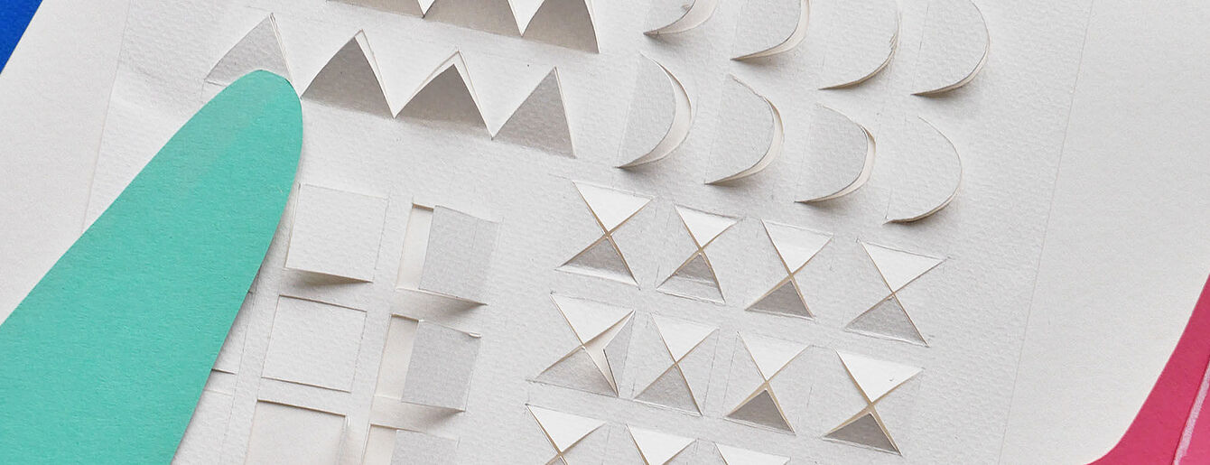 Weißes Papier mit verschiedenen geometrischen Formen als Relief, darunter Dreiecke, Kreissegmente und Quadrate, neben grünem und rotem Papier