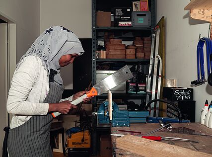 Eine junge Frau arbeitet mit einer Säge in der Werkstatt