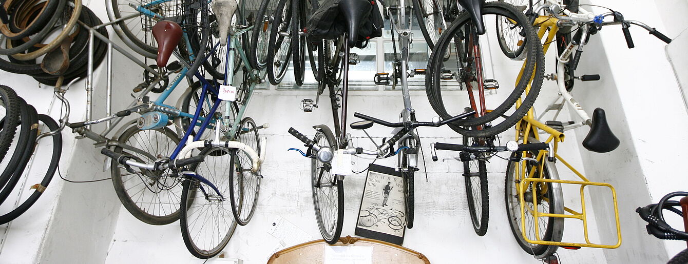 Mehrere Fahrräder und Fahrradrahmen hängen an der Decke eines Raums mit weißen Wänden