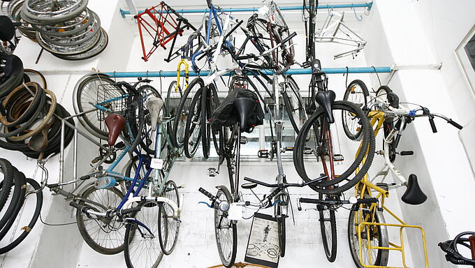 Mehrere Fahrräder und Fahrradrahmen hängen an der Decke eines Raums mit weißen Wänden