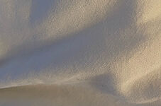 A photograph of warm light over a soft beige linen blanket. Waves of shades and a play of light and depth over its landscape.