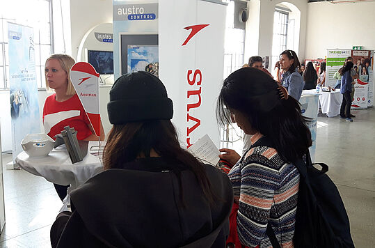Der Stand von Austrian Airlines mit 2 jungen Frauen von hinten