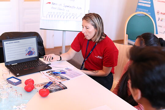 Eine Mitarbeiterin präsentiert Jugendliche beim Casting bei Sodexo etwas am Laptop