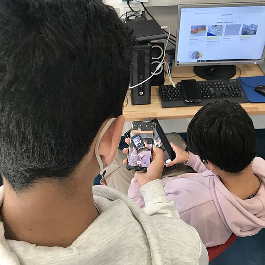 Ein Jugendlicher fotografiert mit dem Handy einen anderen Jugendlichen mit Tablet