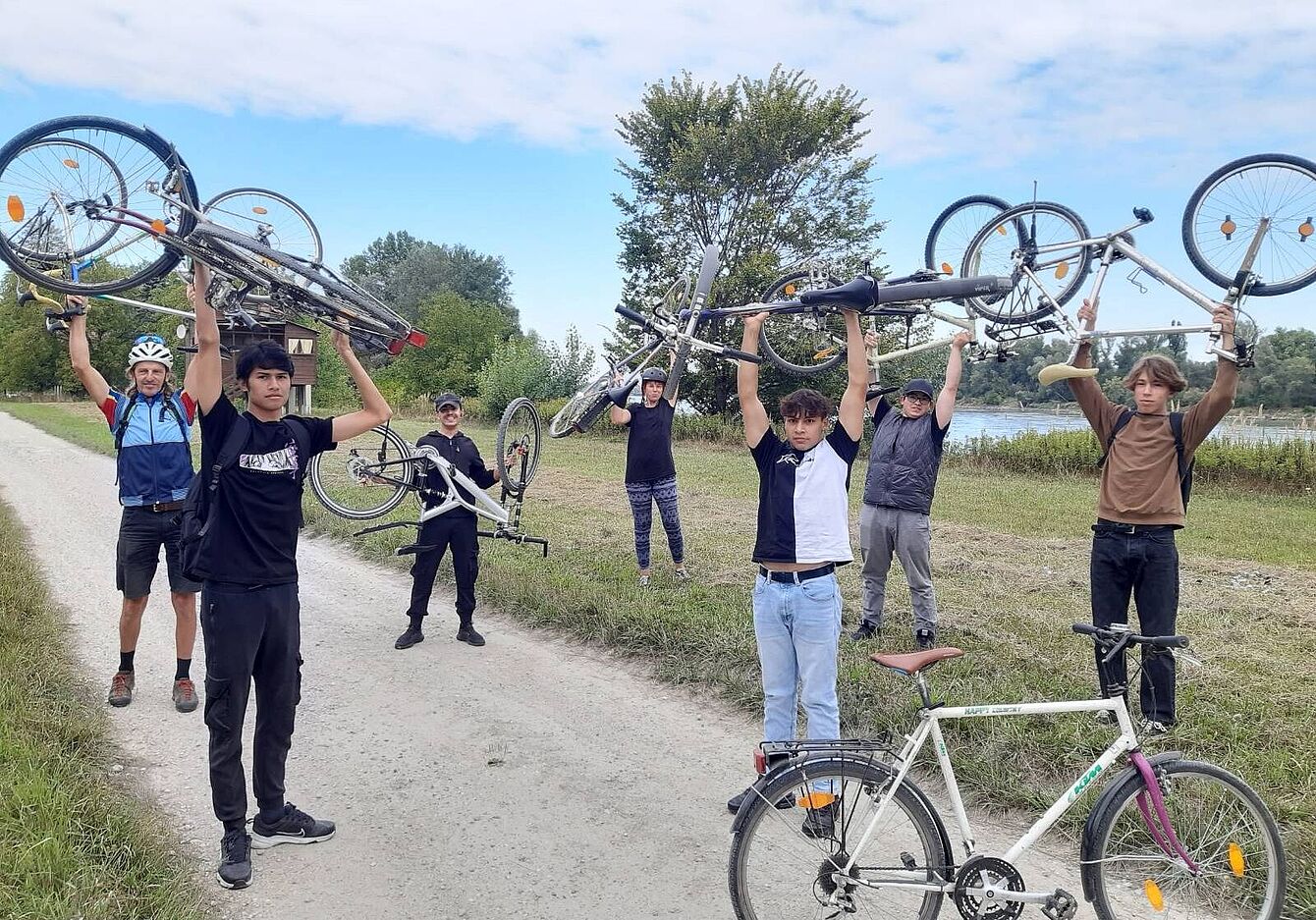 Eine Gruppe von Teilnehmer_innen haltet ihre Fahrräder über ihren Köpfen