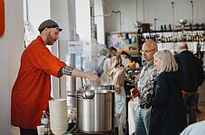 Mann in rotem Arbeitsmantel schenkt Suppe aus