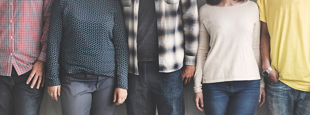 Photo by rawpixel.com on Unsplash Fünf Personen stehen nebeneinander, nur Oberkörper und Beine sichtbar, verschiedene lässige Kleidung