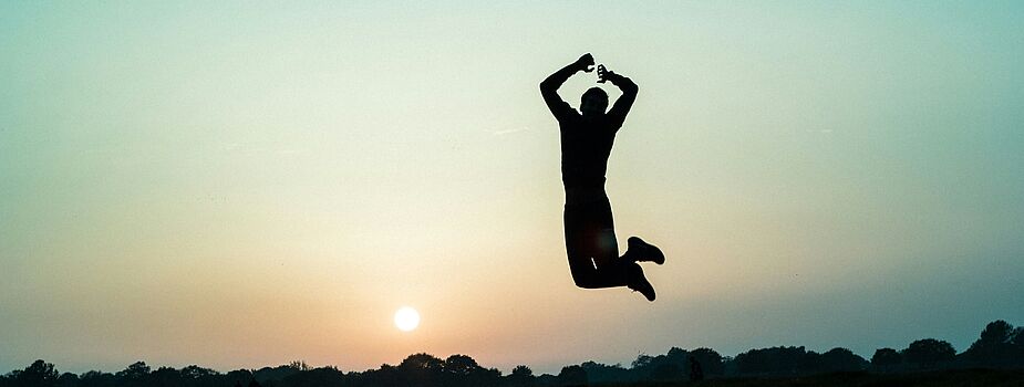Silhouette einer Person, die bei Sonnenuntergang in die Luft springt