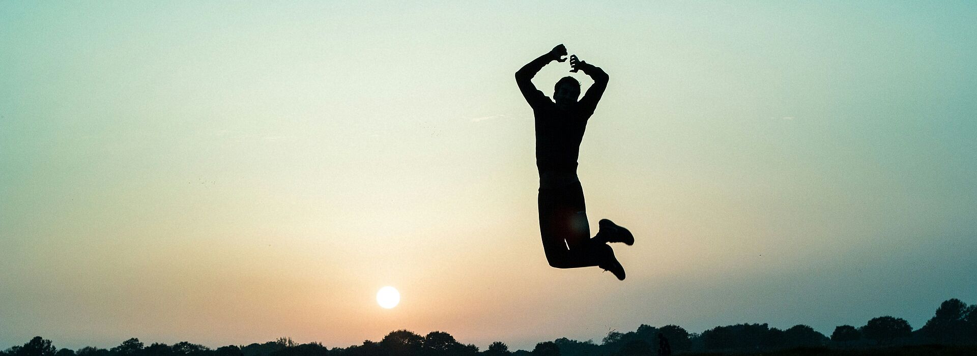 Silhouette einer Person, die bei Sonnenuntergang in die Luft springt