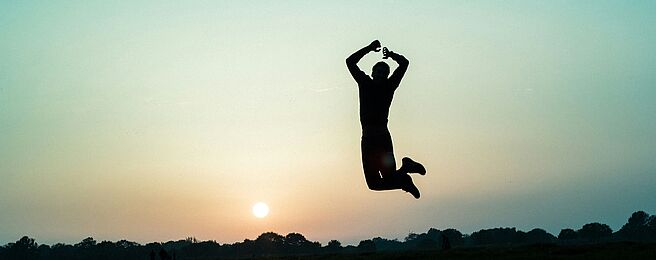 Silhouette einer Person, die bei Sonnenuntergang in die Luft springt
