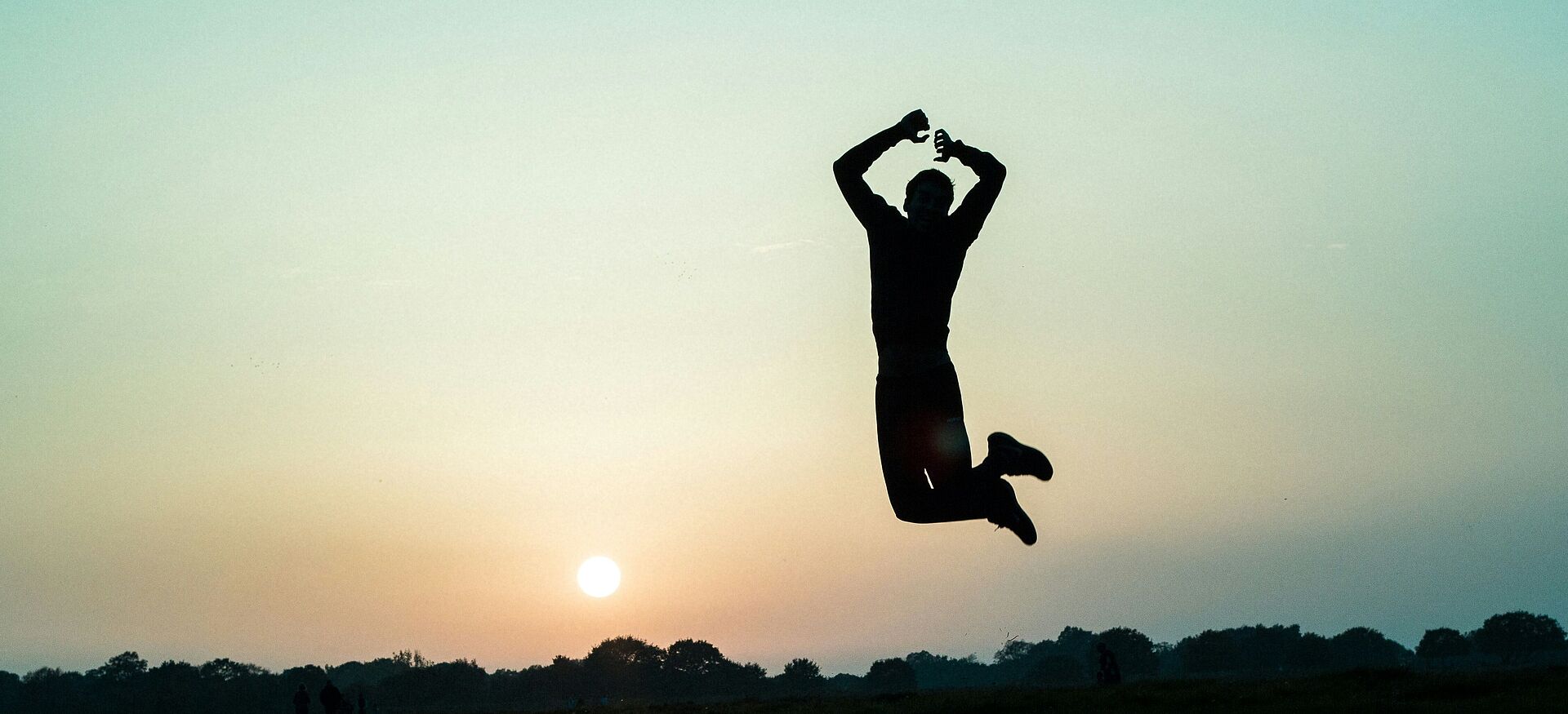 Silhouette einer Person, die bei Sonnenuntergang in die Luft springt