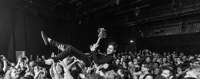 Stagediver mit Gitarre, schwarz-weiß-Fotografie