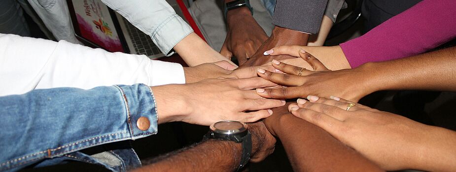 Mehrere Hände liegen übereinander in der Mitte eines Kreises