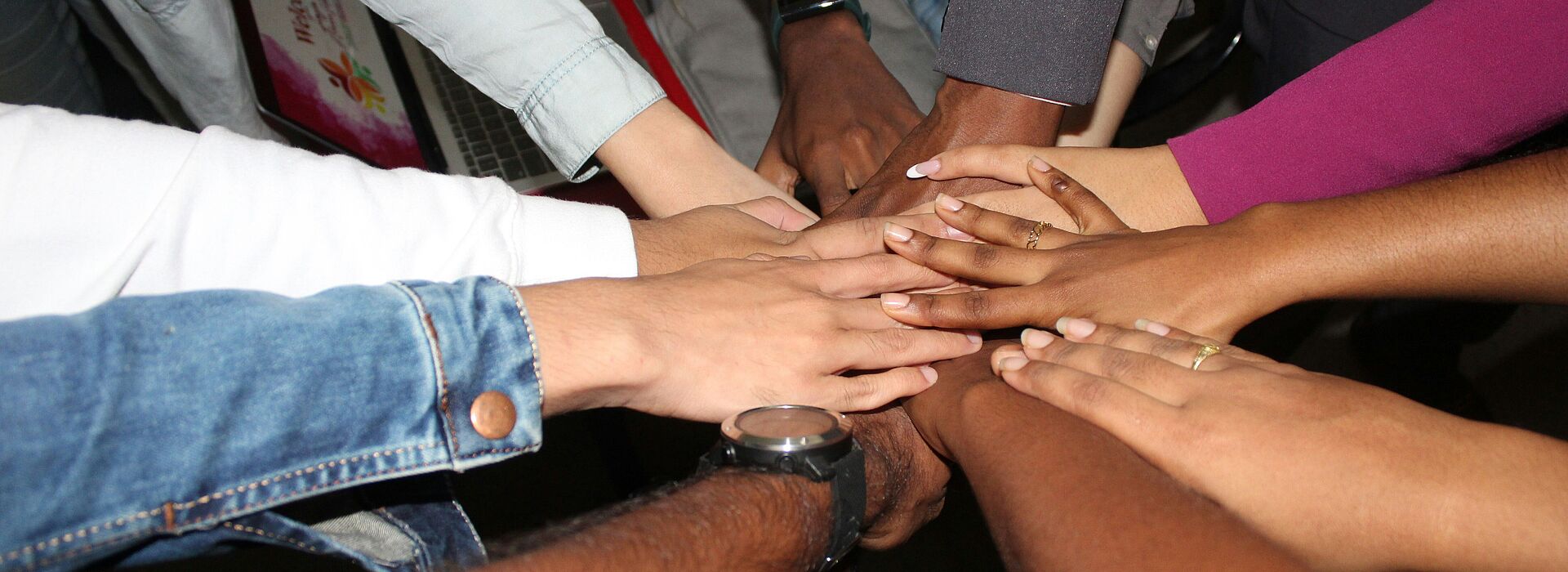 Mehrere Hände liegen übereinander in der Mitte eines Kreises