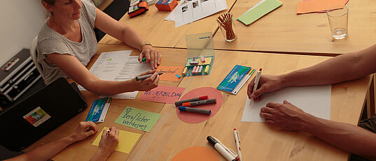 Gruppenberatung mit Trainerin und Arbeitsmaterialien am Tisch