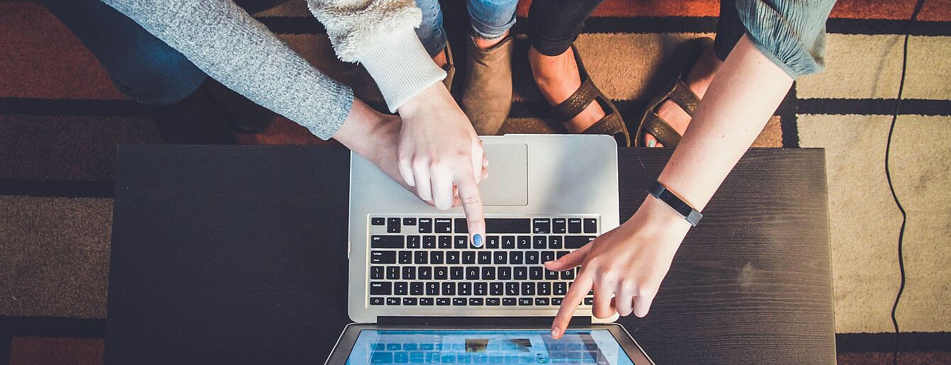 Zwei Personen zeigen auf den Bildschirm eines Laptops während einer Bildungsberatung