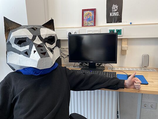 Ein Teilnehmer mit selbstgebastelter Bärenmaske vor dem Computer
