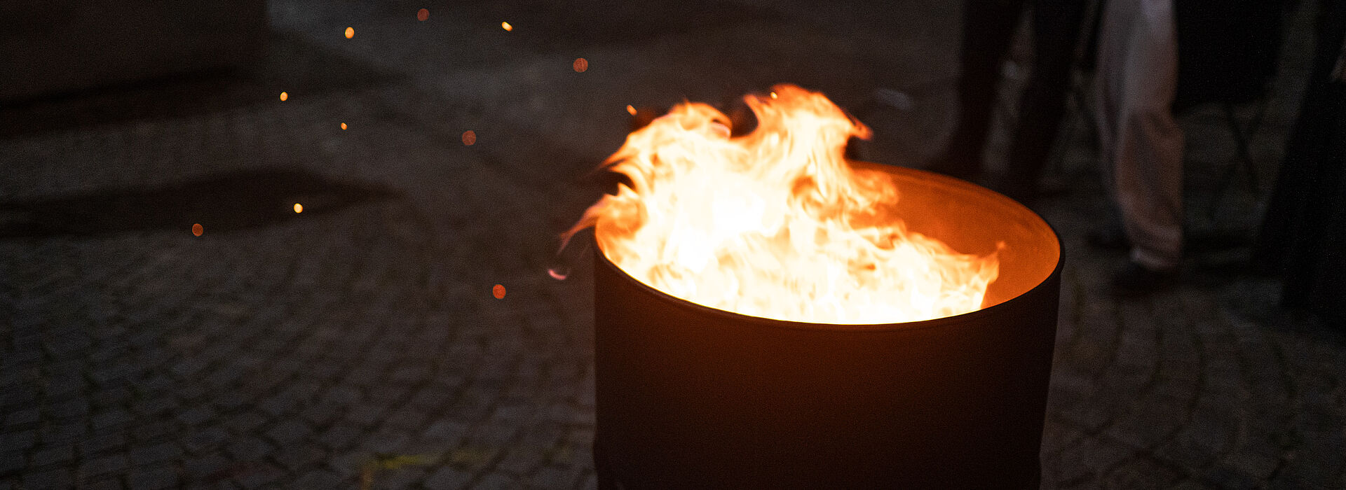 Das Bild zeigt eine Metalltonne mit brennendem Feuer