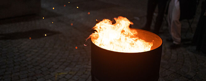 Das Bild zeigt eine Metalltonne mit brennendem Feuer