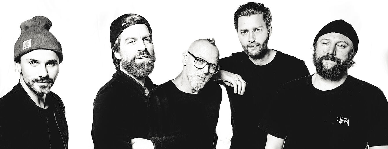 schwarz-weiß Foto von 5 Männern, die nebeneinander stehen und in die Kamera blicken. Thomas D steht mittig.