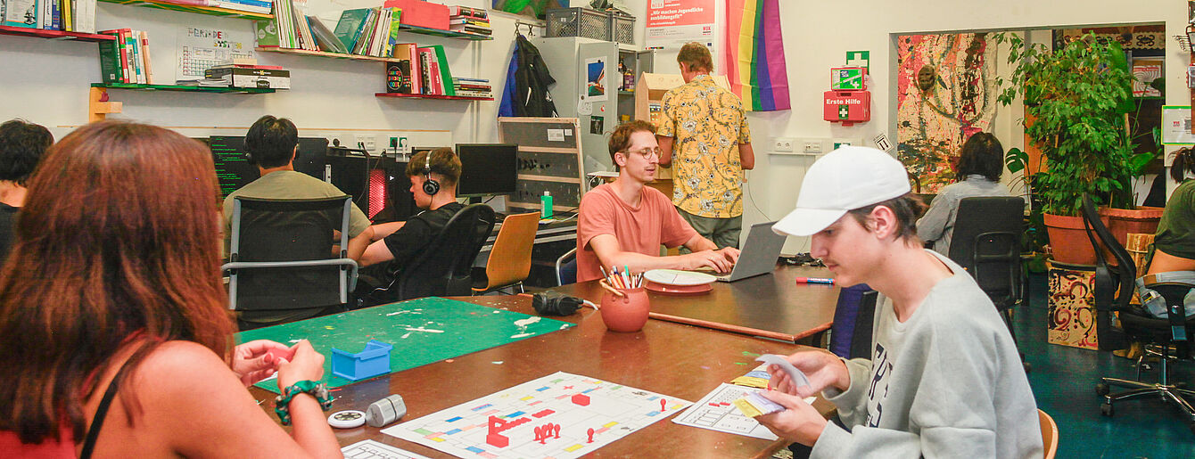 Foto: WUK Mehrere Personen sitzen an einem großen Tisch in einem hellen Raum und spielen Brettspiele