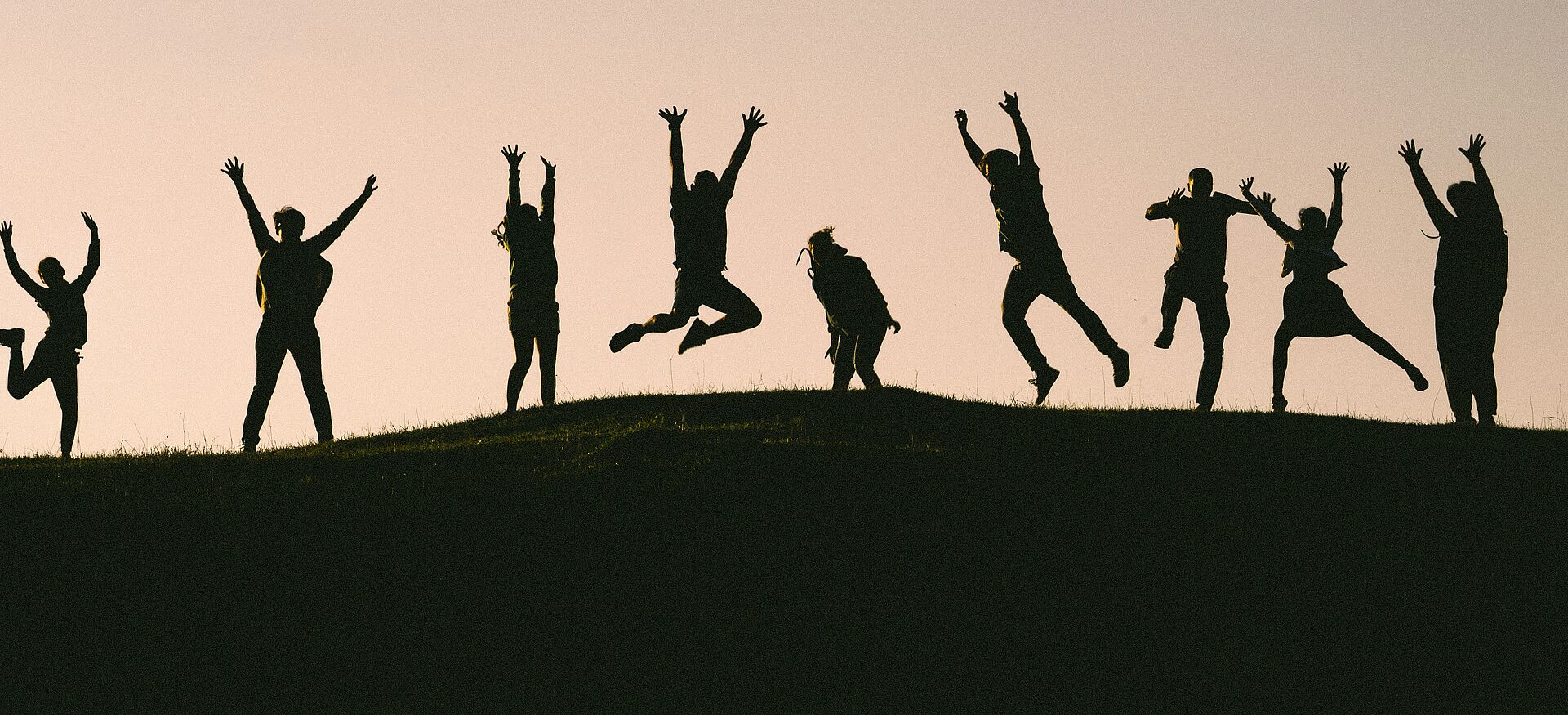 Photo by Val Vesa on Unsplash Silhouetten mehrerer Menschen, die auf einem Hügel springen und Arme heben