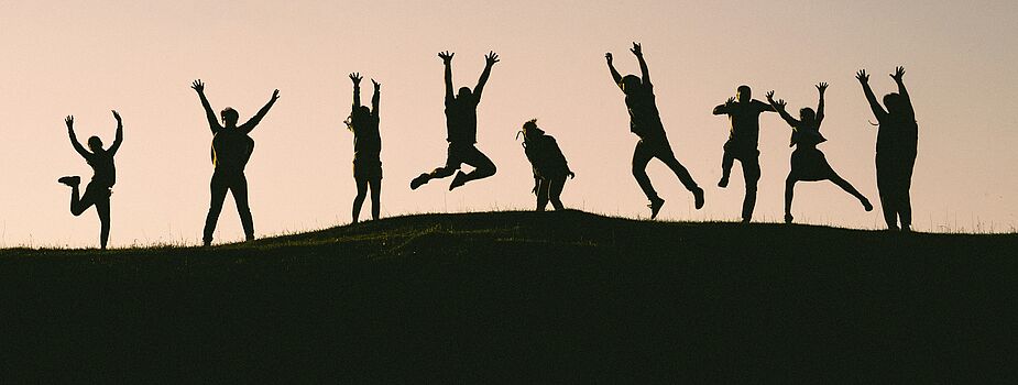 Photo by Val Vesa on Unsplash Silhouetten mehrerer Menschen, die auf einem Hügel springen und Arme heben