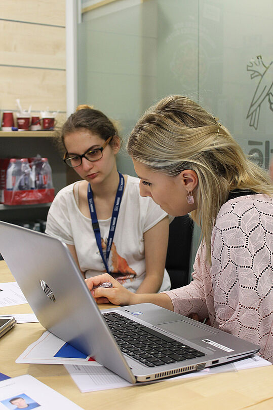 Eine Frau zeigt einer Jugendlichen etwas am Computer