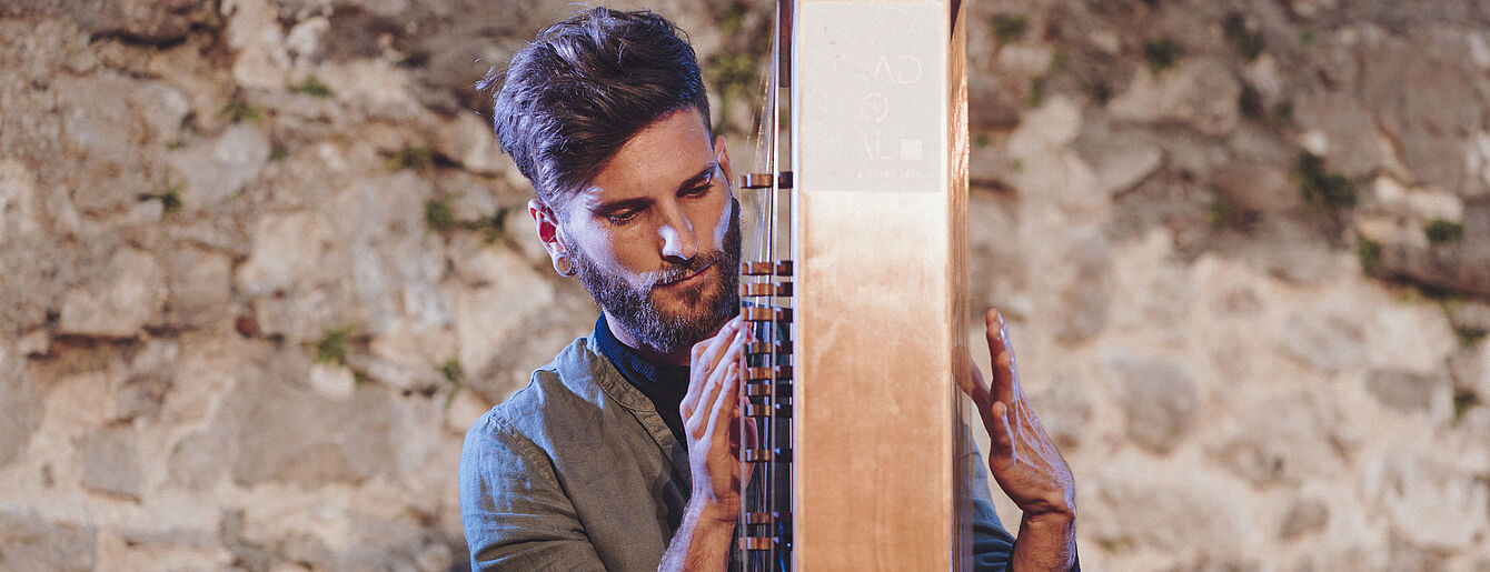 Person spielt auf einem großen Holzinstrument bei einem Liegekonzert vor einer Steinwand