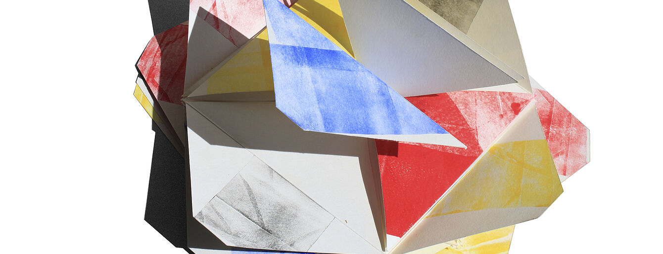 Bunte, dreidimensionale Papierform aus gefalteten Dreiecken mit roten, blauen, gelben und schwarzen Farbflächen.