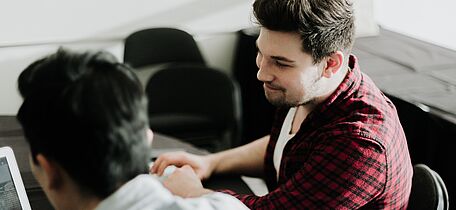 2 Menschen sitzen vor einem Computer