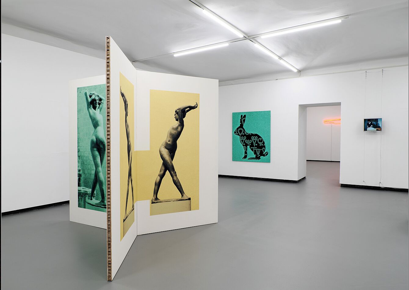 Ausstellung mit großformatigen Fotografien von nackten Frauen in verschiedenen Posen auf weißen Stellwänden und an der Wand in einem hellen Raum.