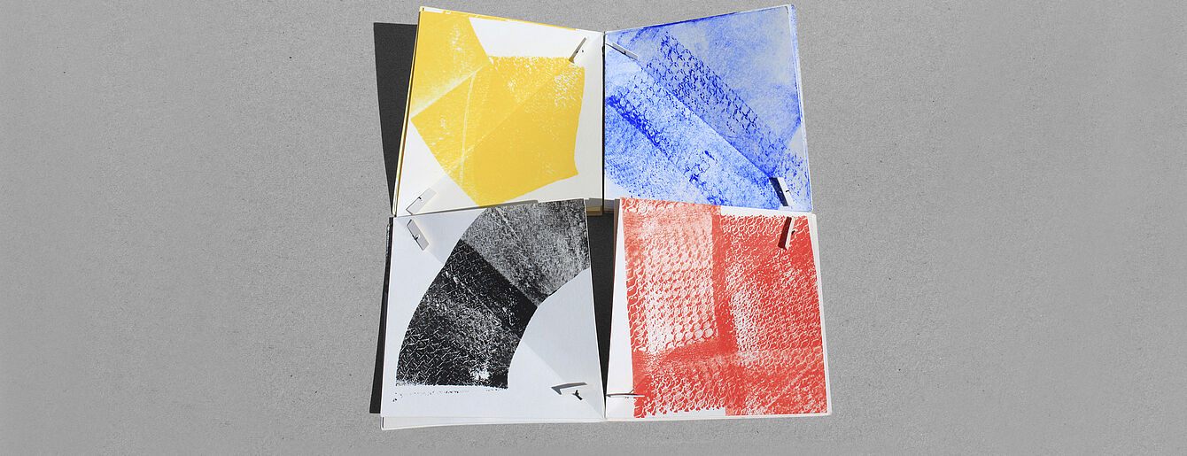 vier aneinander gelegte REchtecke mit den Grundfaben und Schwarz bedruckt