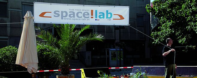 Eine Person spannt einen spacelab-Banner auf