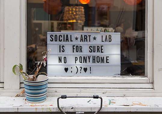 ein Fenster mit dem Schild "social.art_lab is for sure no ponyhome"