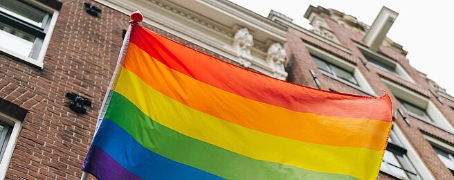 Eine Regenbogenfahne vor einem Gebäude