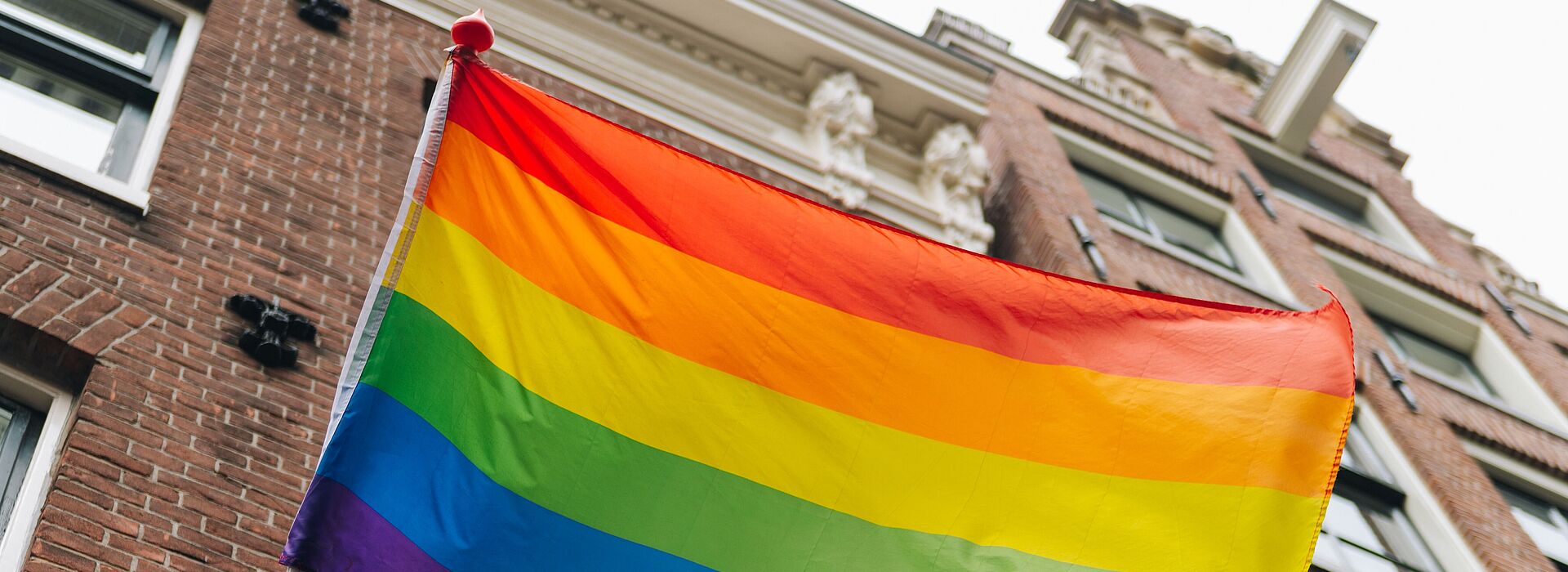 Eine Regenbogenfahne vor einem Gebäude