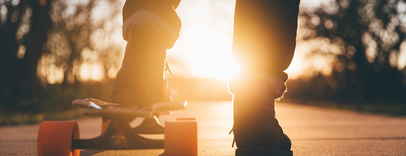 Füße am Skateboard im Gegenlicht