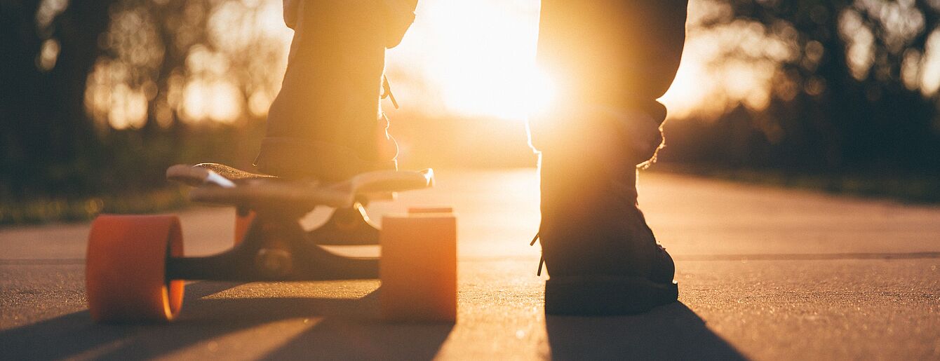 Füße am Skateboard im Gegenlicht